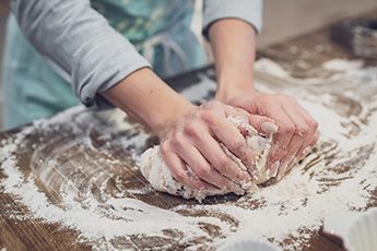 Women’s hands kneading dough on floured table